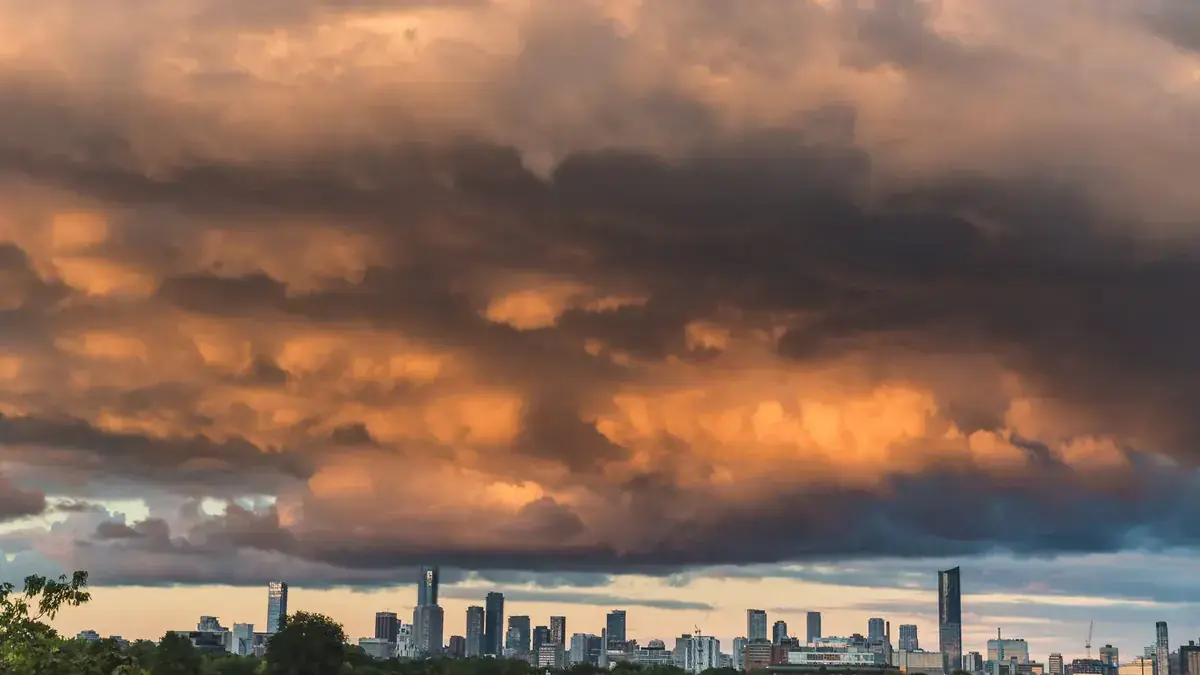 Orange storm clouds blaze above a city skyline at sunset (Leo and Scorpio compatibility)
