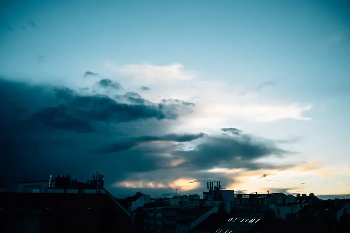 Storm clouds break apart over a town as evening light pours through (Libra and Capricorn compatibility)