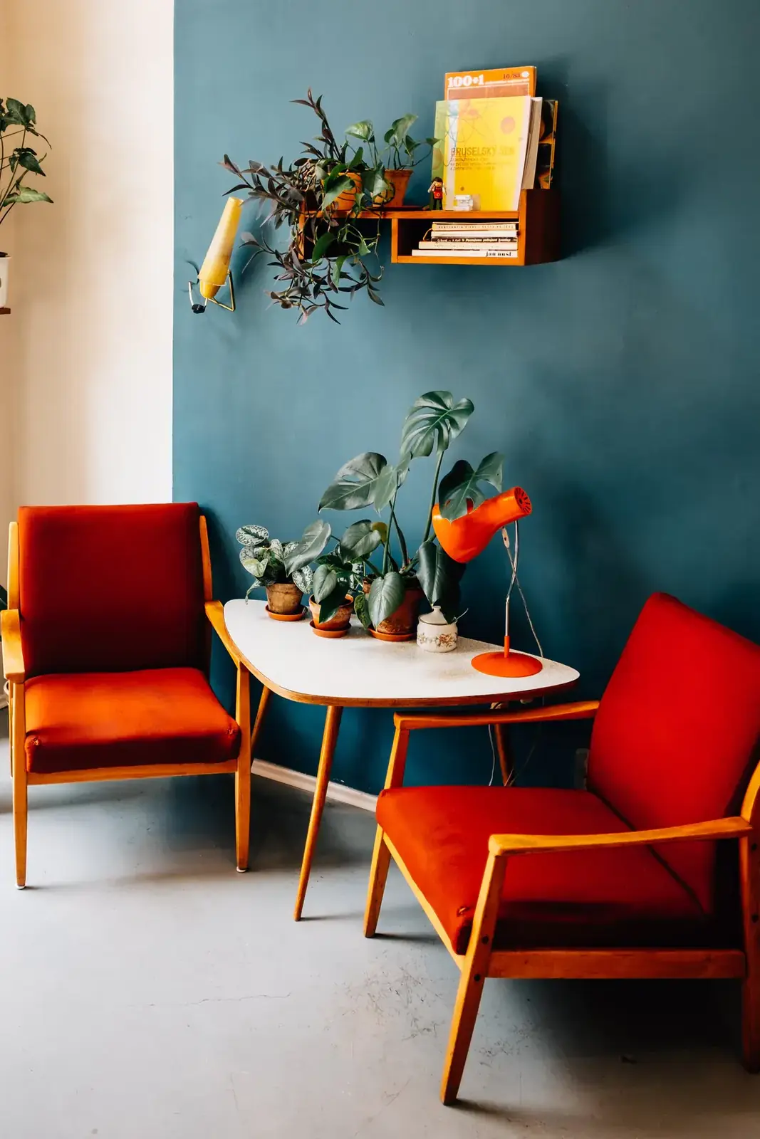 Two red armchairs face each other across a small table against a teal wall (Libra with Libra compatibility)