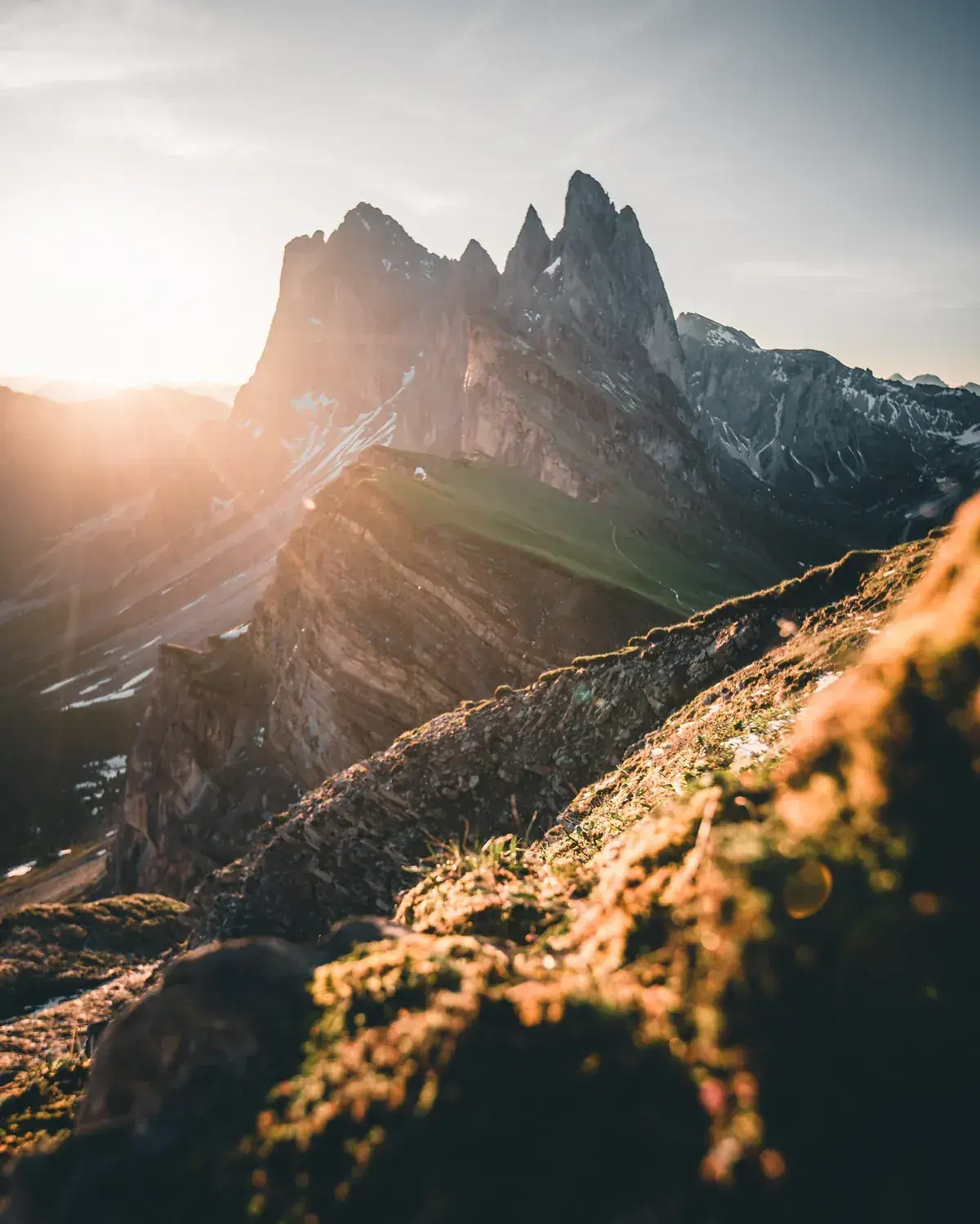 Sunlight catches the craggy summit of a mountain above a grassy ridge (Capricorn with Capricorn compatibility)