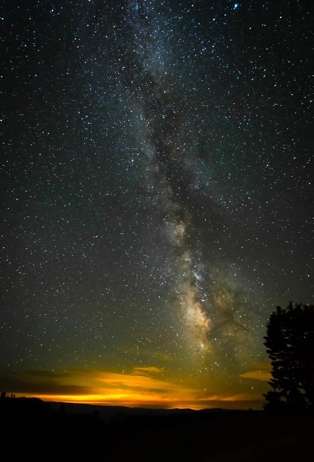 The Milky Way over a plain and a band of orange horizon light