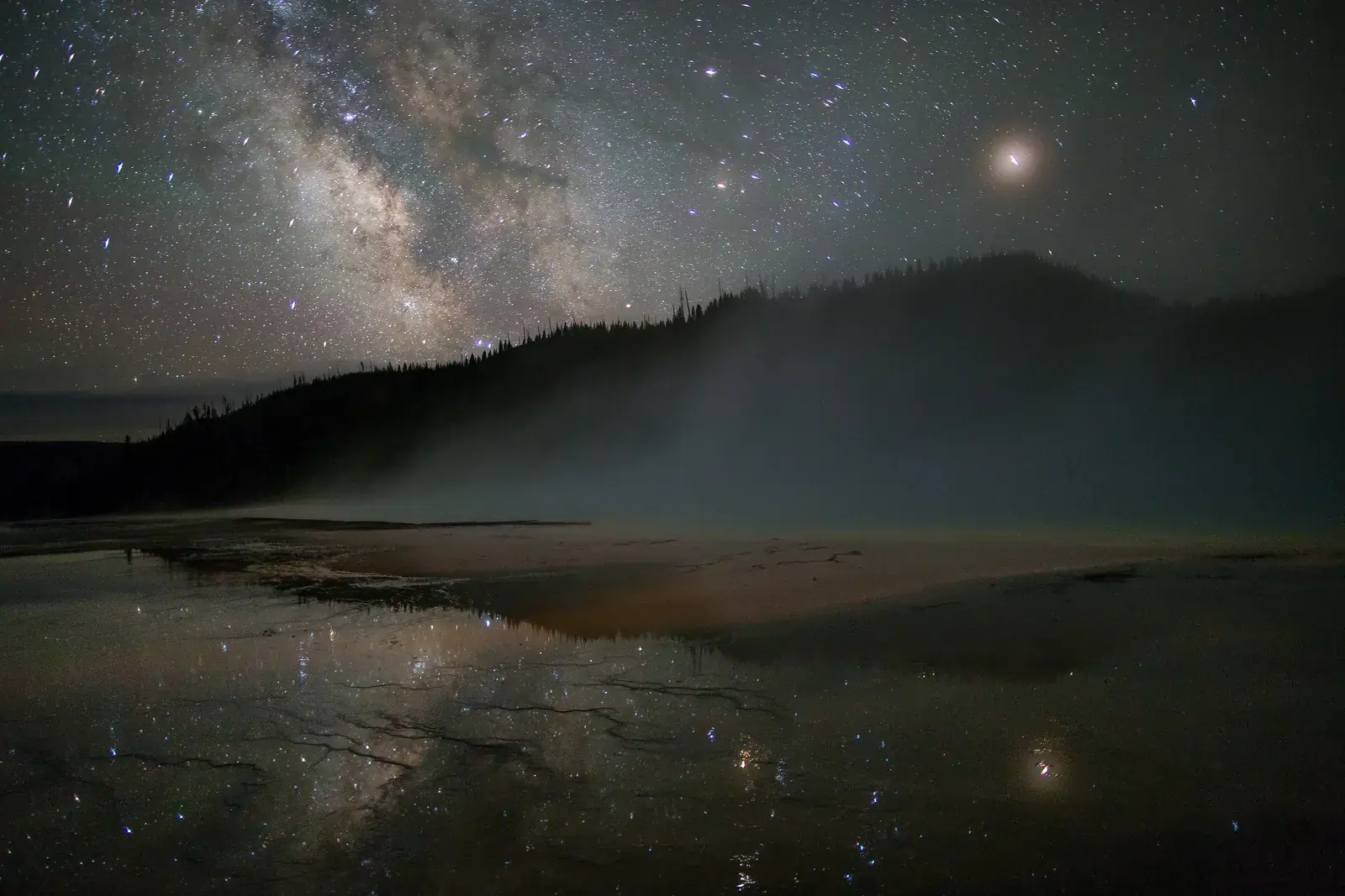 The Milky Way and a bright planet over the steaming Grand Prismatic Spring