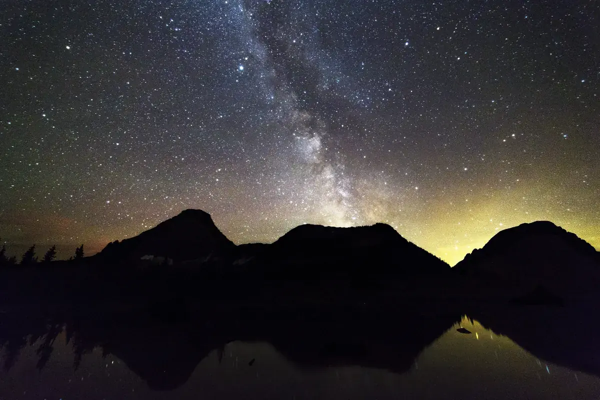 The Milky Way and dark peaks mirrored in a still alpine lake