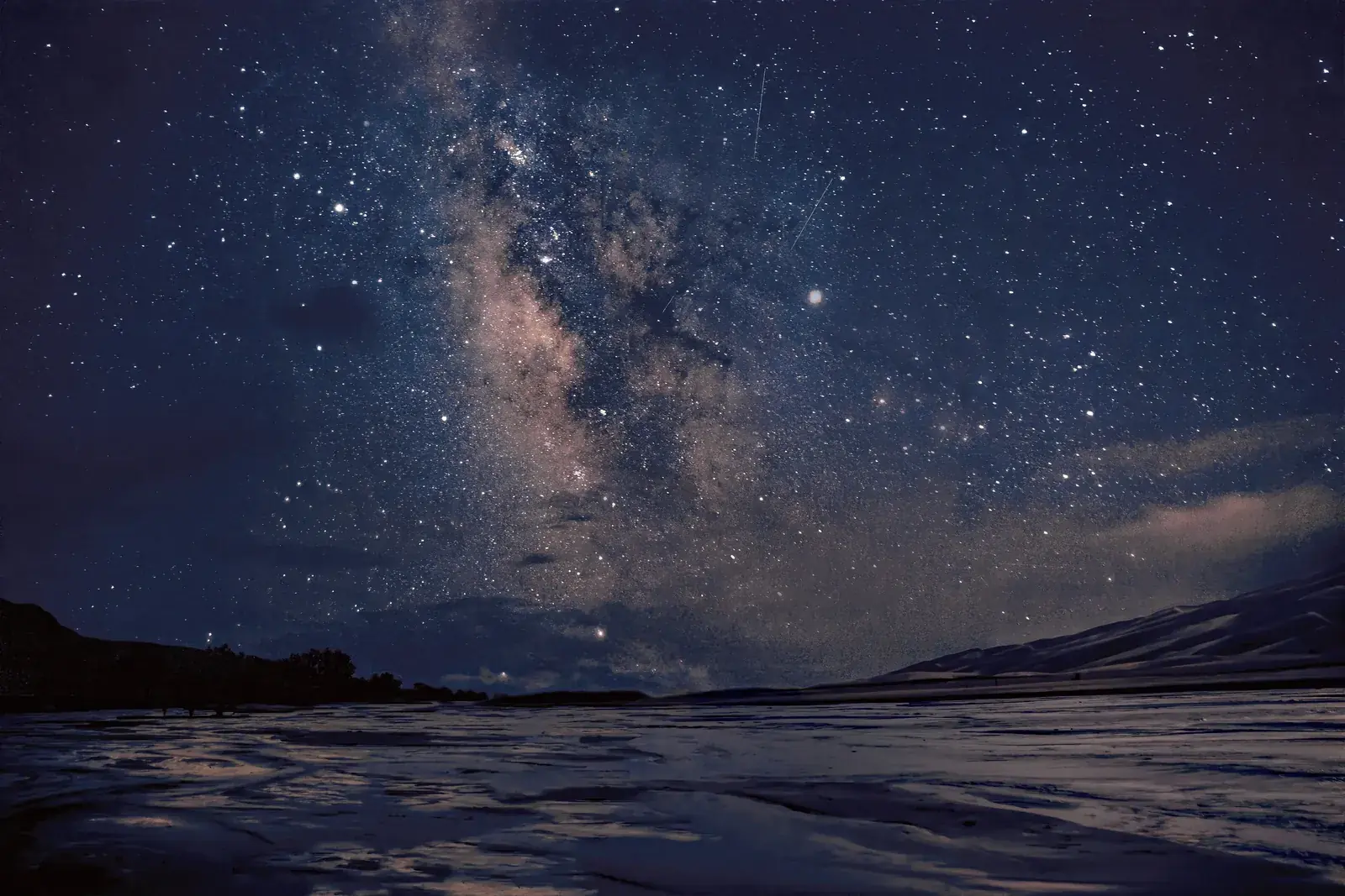 The Milky Way glowing over Medano Creek and the dunes