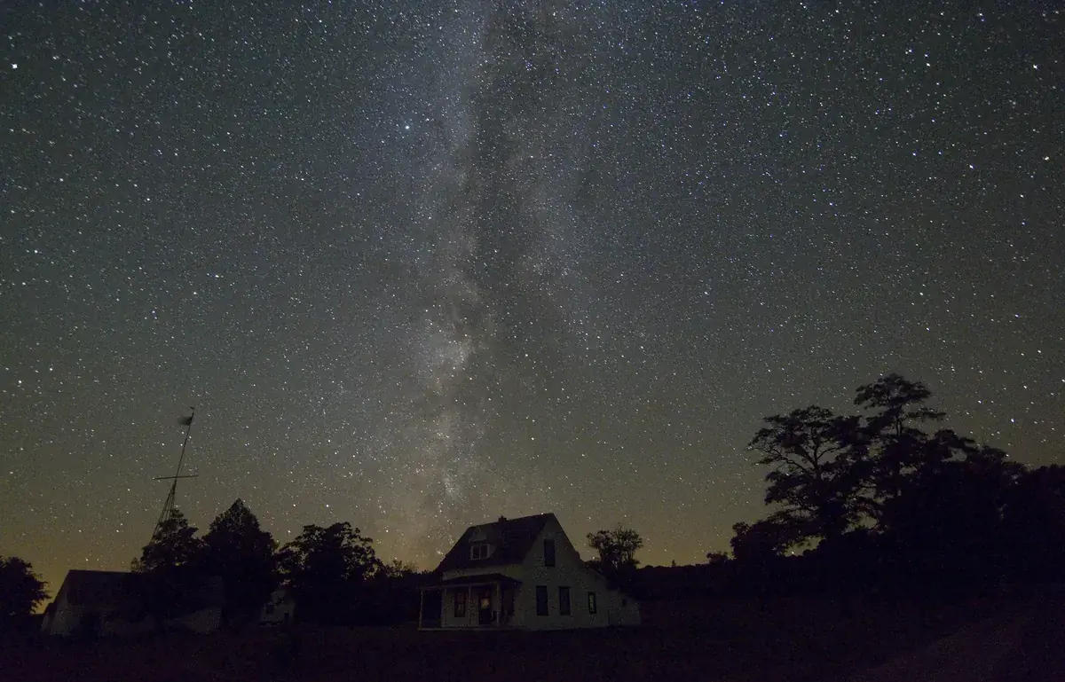 The Milky Way over a quiet island village and its trees
