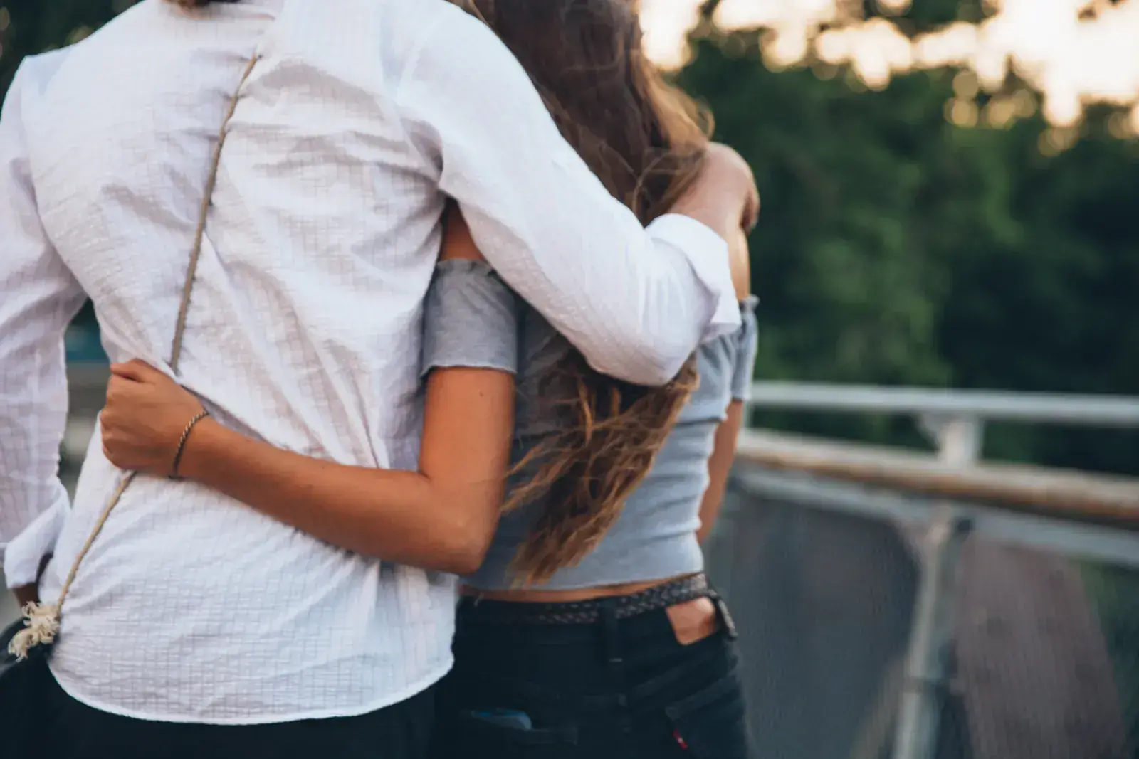 A couple hugging close by a railing, seen from behind